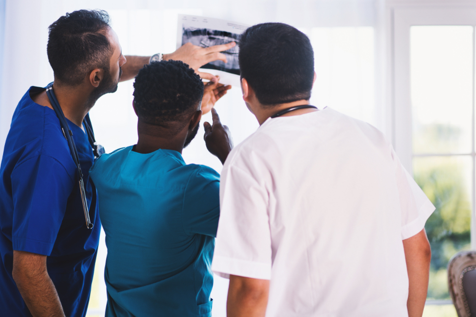 A care team reading an X-ray on a light board