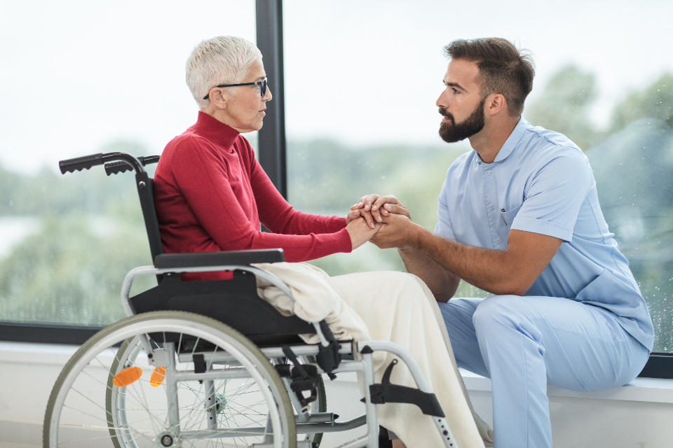 A patient care technician helping a patient in a wheelchair